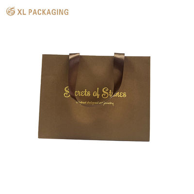 Luxe papieren cadeautsaag met gouden folie met warm stempel, brede satine lintgrepen en driehoekige opvouwbare bodem